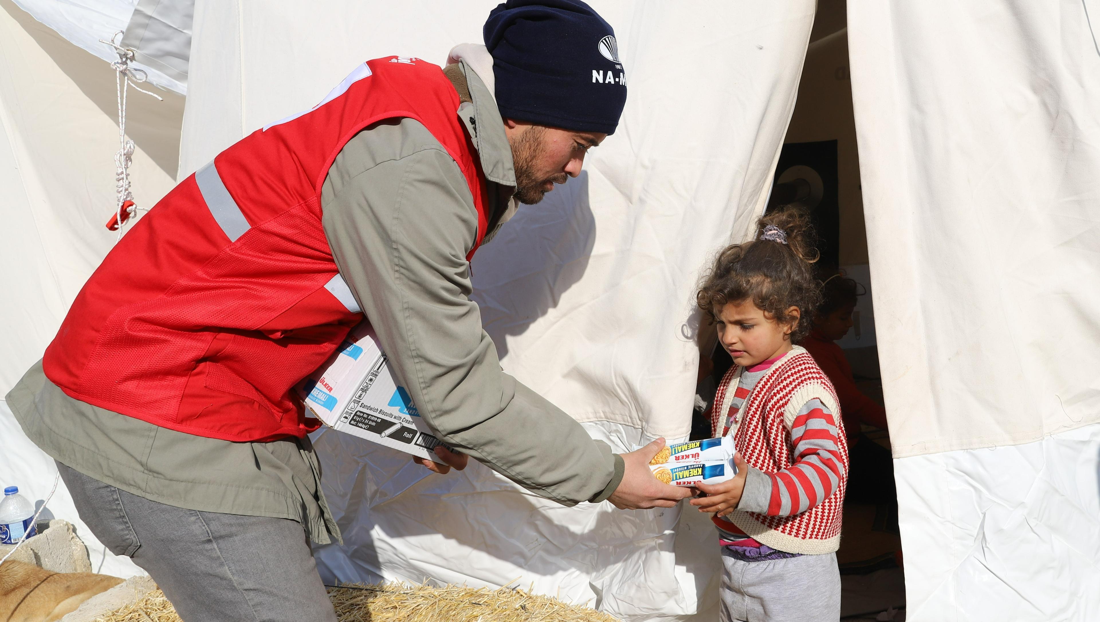 Le Croissant-Rouge distribue des vivres aux survivants du séisme dans un camp de tentes en Turquie. 