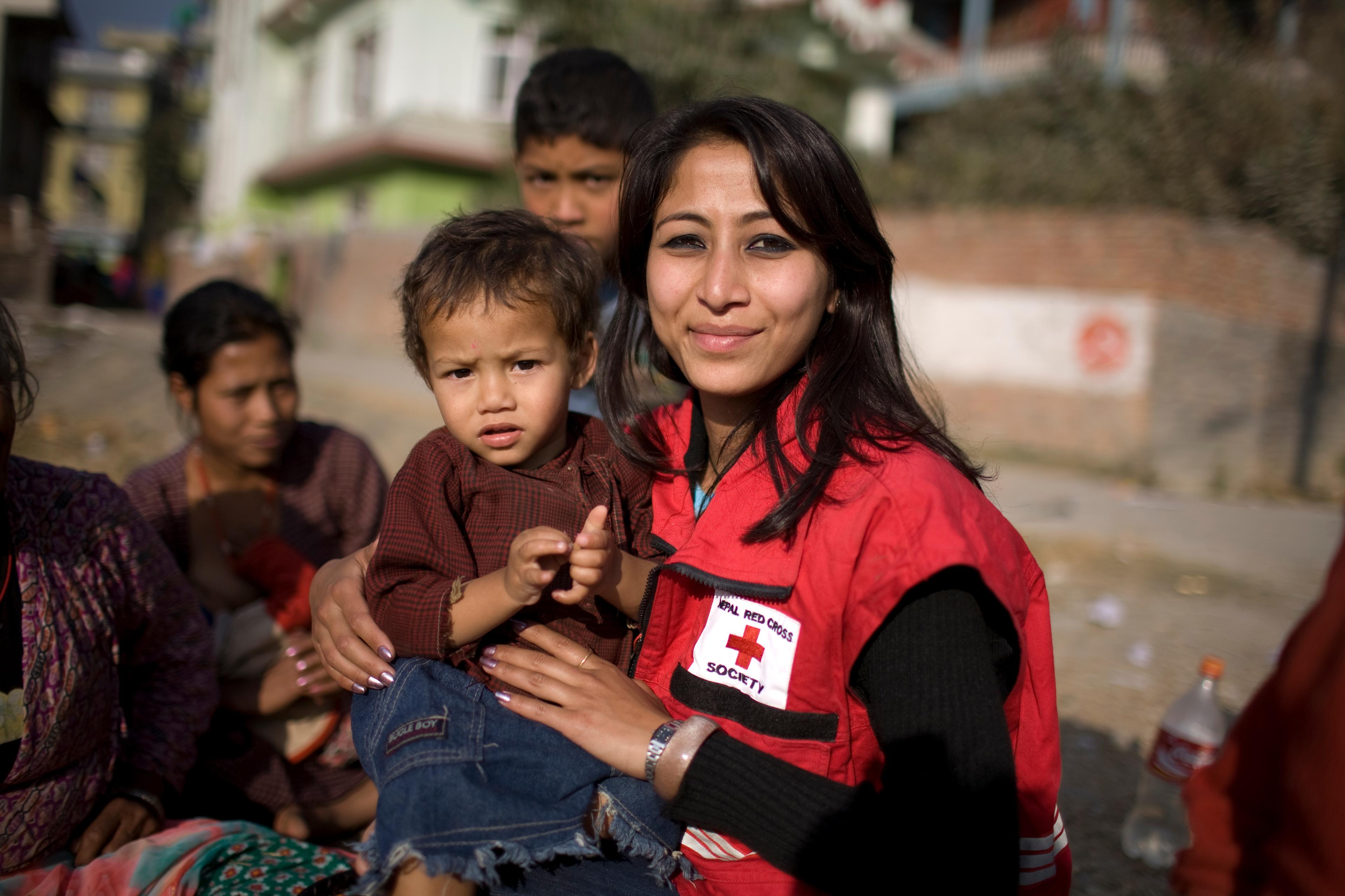 Une bénévole de la Croix-Rouge tient un enfant dans ses bras. 