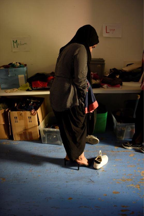 Una donna è in piedi davanti a un tavolo da rovistaggio e sta provando delle scarpe.