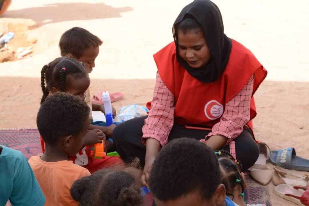 Un volontario della Mezzaluna Rossa Sudanese gioca con i bambini piccoli.