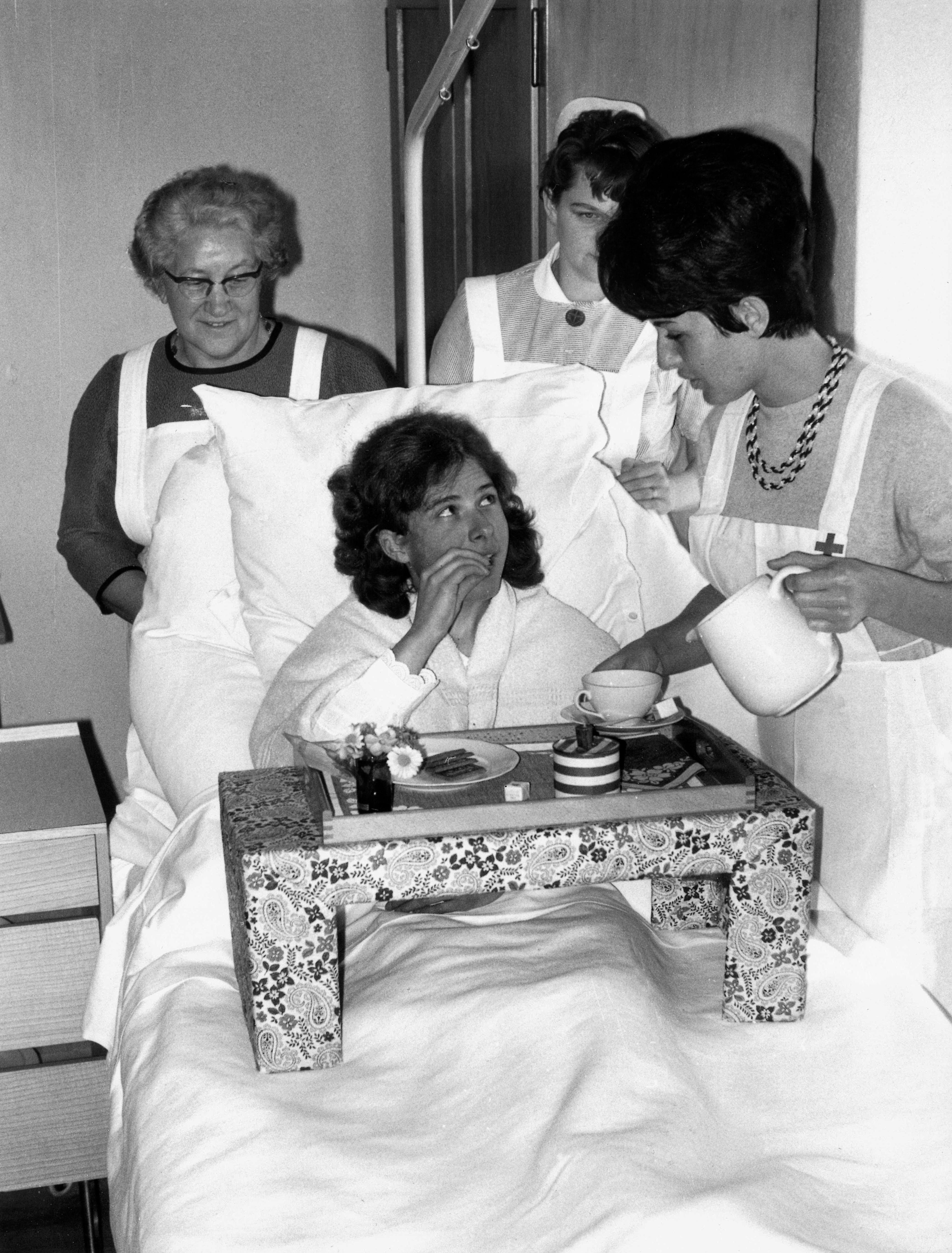 Historisches Bild aus dem Archiv, schwarz-weiss Foto: Pflegehelferinnen SRK bereiten einer Patientin das Essen zu.