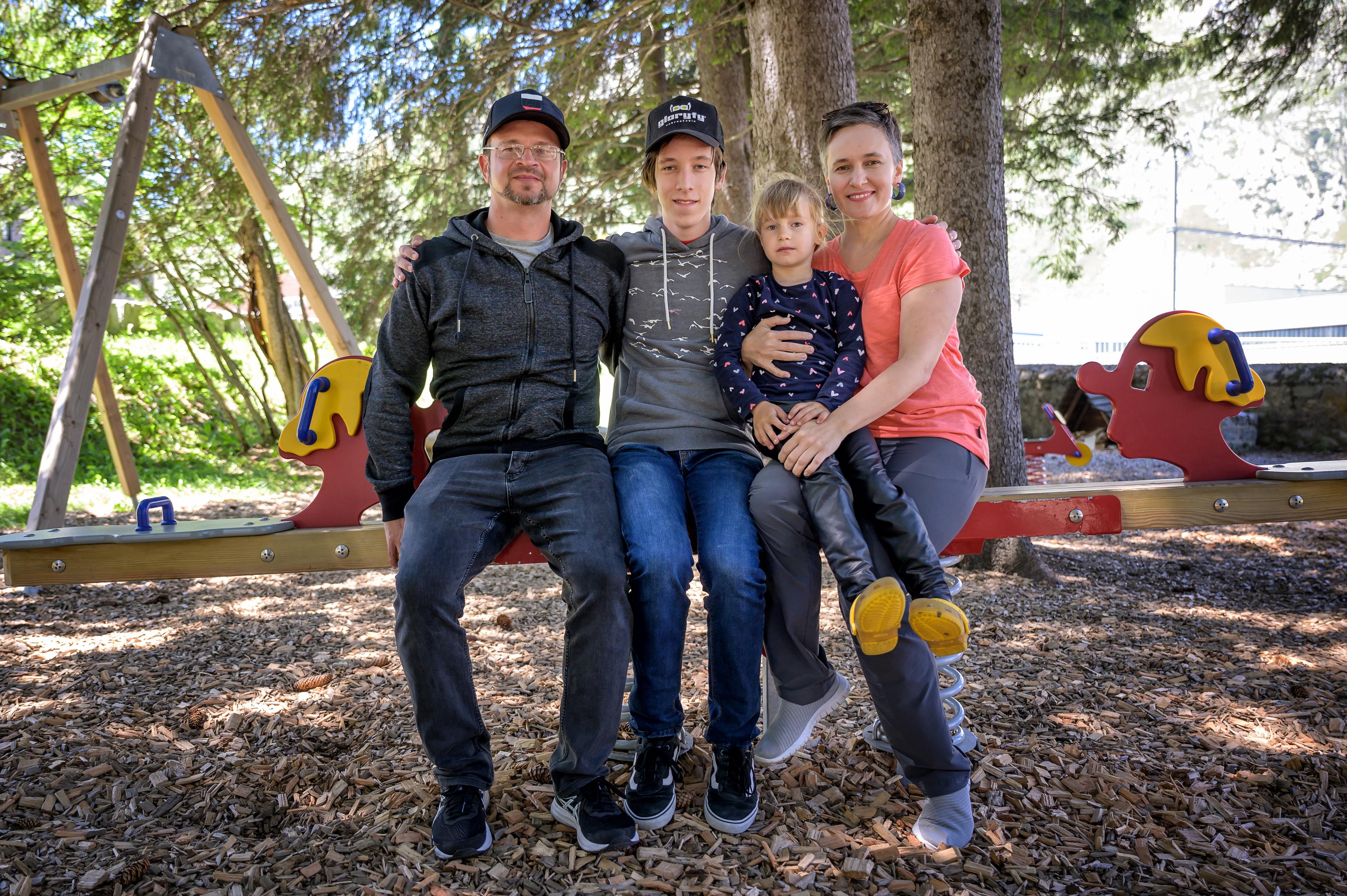 Due ukrainischischen Geflüchteten Natalia und Oleksiy Makiienko mit den Kindern Vlad und Diana. Sie sitzen auf einer Schaukel auf einem Spielplatz.