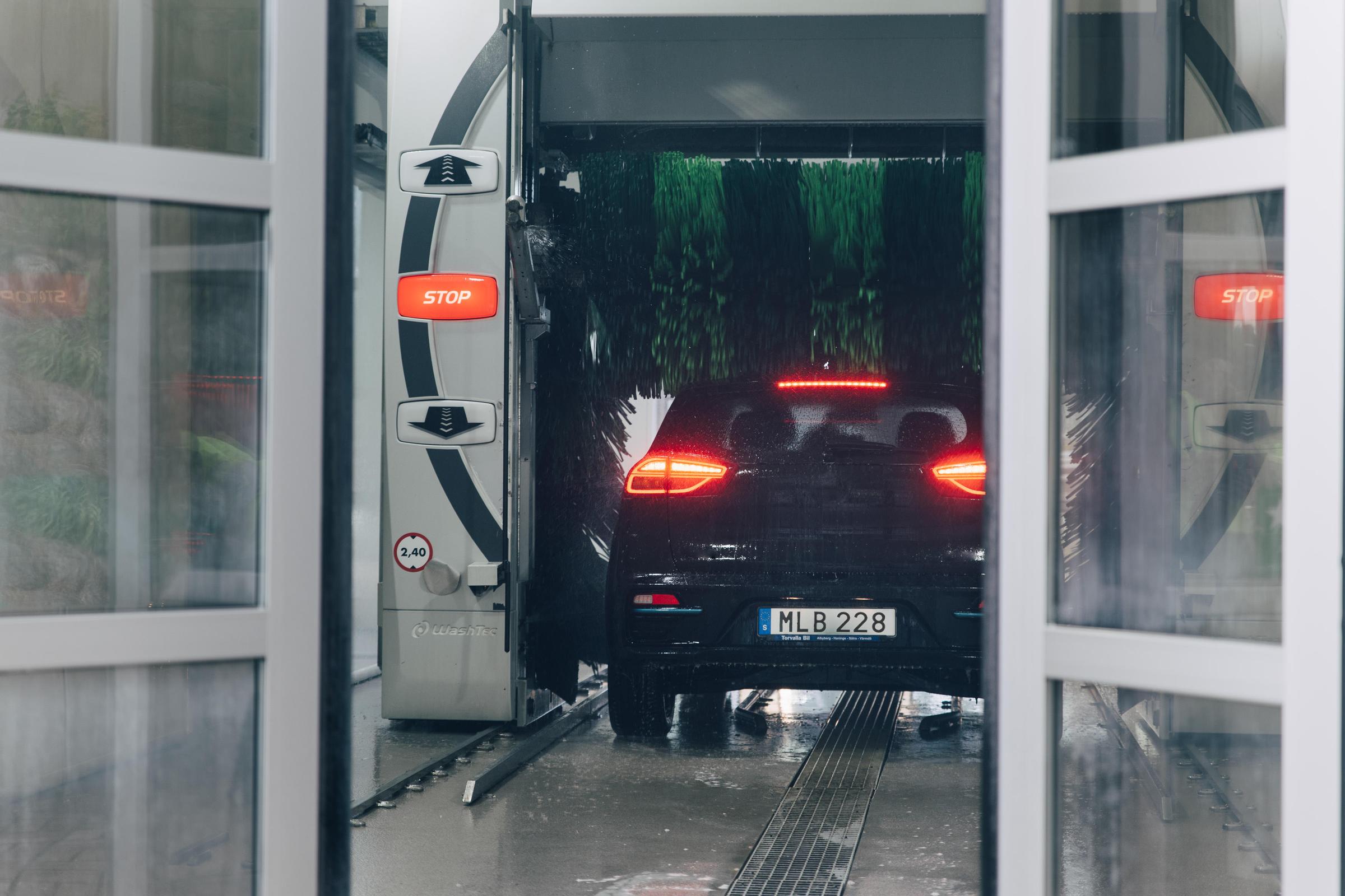 Svart bil i biltvätt, dörrar som stängs