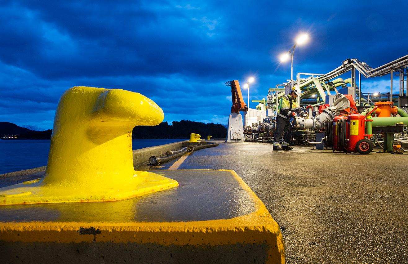 Vitklädd kapten på ett fartyg ler stort och gör honnör från däck.