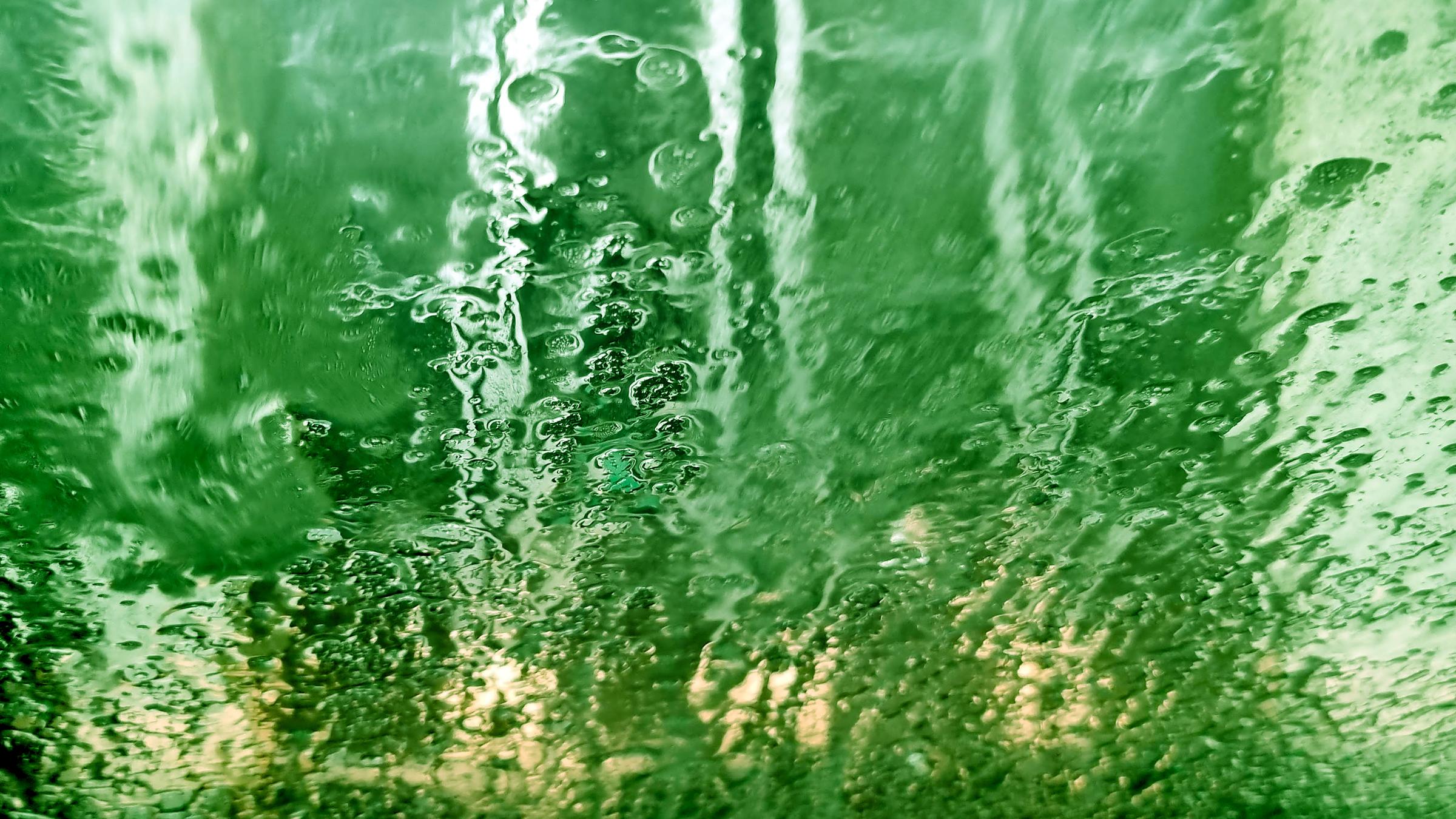 Grön tvättborste fotograferad innifrån en bil i en biltvätt