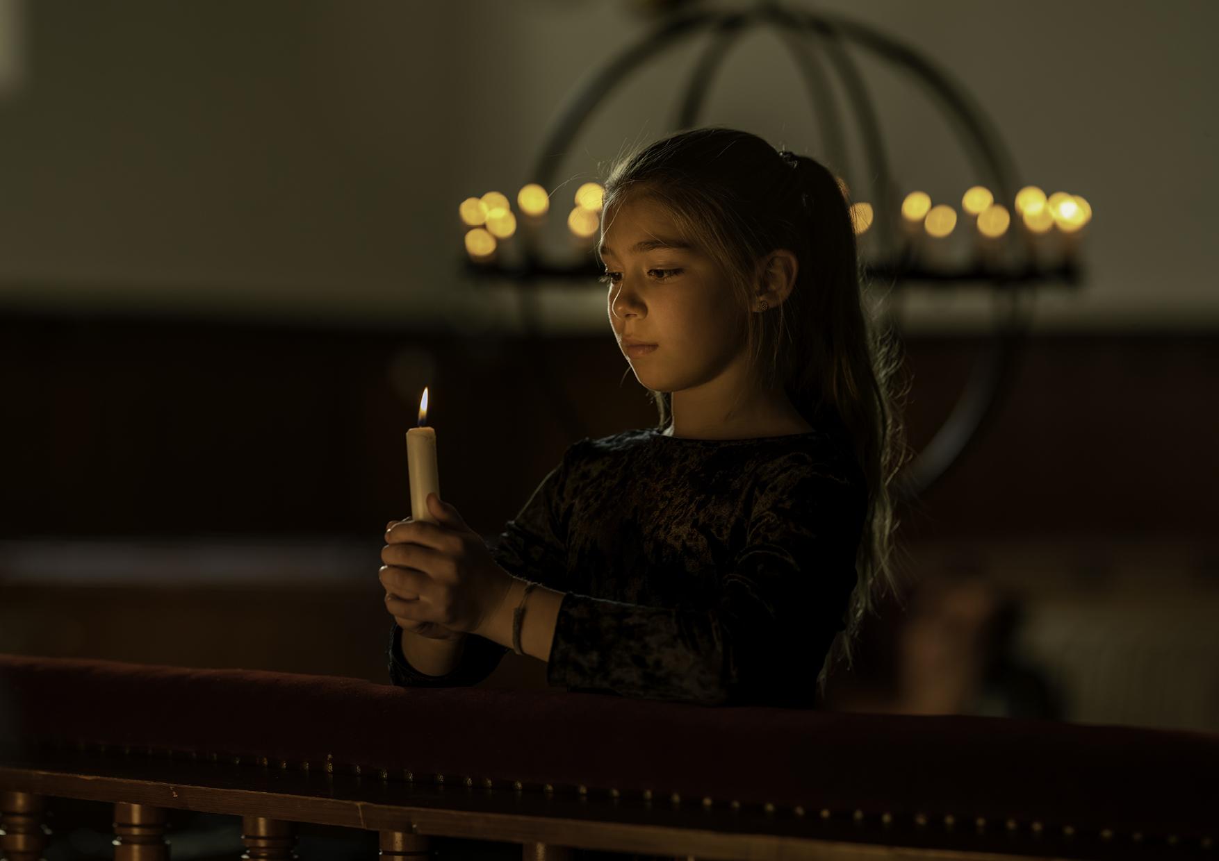 Jente holder tent lys i kirke