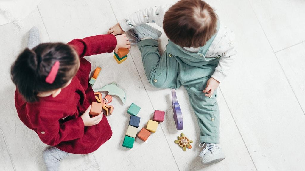 To barn som leker med figurer på gulvet