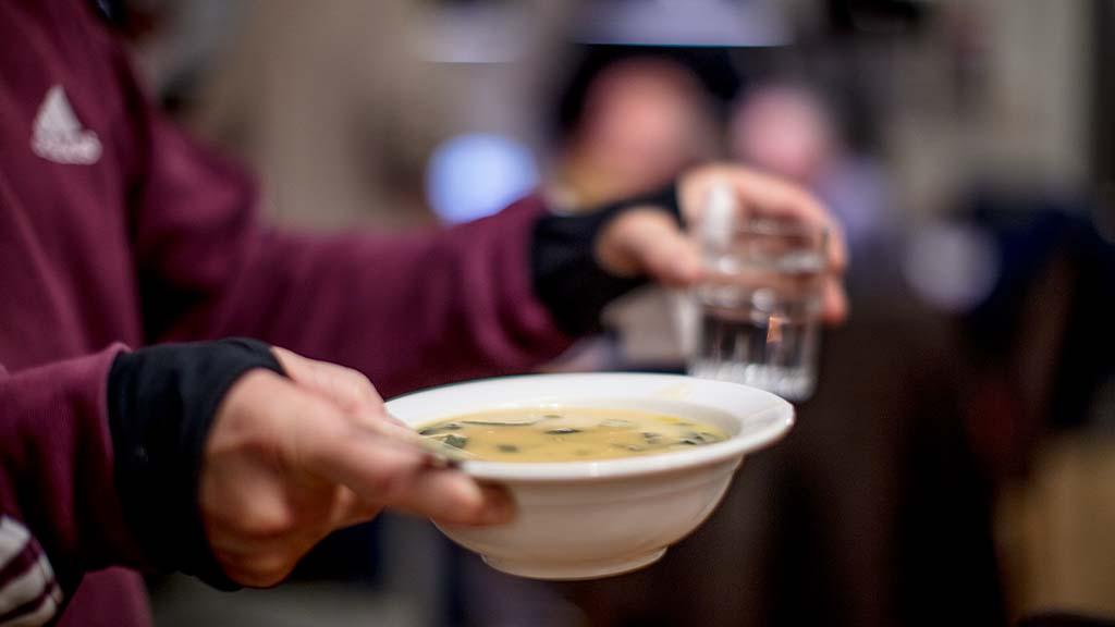 Person holder en skål med suppe